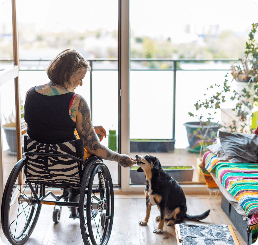 Person in wheelchair with dog indoors.