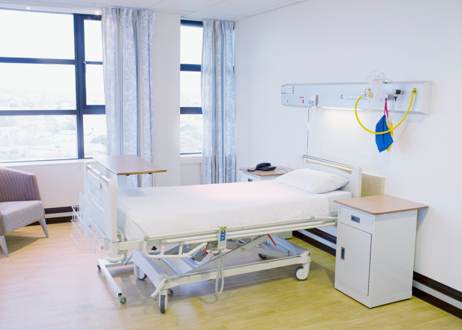 A clean hospital room with a bed and medical equipment.